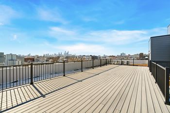 A wooden deck with a metal railing overlooking a city skyline.